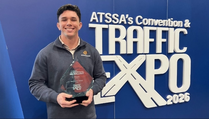 A person holding a glass award smiles at the camera at the ATSSA's Convention & Traffic Expo 2026. They stand in front of a blue backdrop.